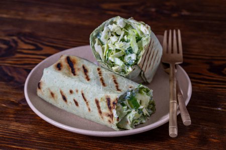 Téléchargez les photos : Burrito maison enveloppements au chou vert, concombre, herbes et crème sure pour un petit déjeuner sain sur assiette, fermer - en image libre de droit