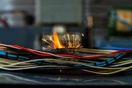 Photo for Flames, sparks, smoke between electrical cables, close up. Short circuit in the twisted wires from the electrical devices, fire hazard concept - Royalty Free Image
