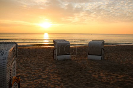 Téléchargez les photos : Décor romantique avec chaises longues au bord de la mer au lever du soleil - en image libre de droit