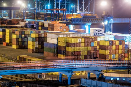 Foto de Container terminal in industrial port with cranes. Sea port container terminal during work at night. Industrial theme - Imagen libre de derechos
