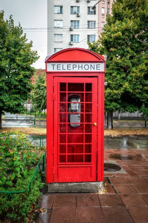 Foto de Caja de teléfono roja en la calle bajo la lluvia - Imagen libre de derechos