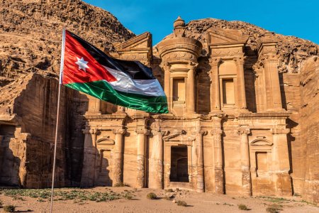 Foto de Bandera de Jordania frente a un templo Ad-Deir en ruinas de la antigua ciudad de Petra. - Imagen libre de derechos