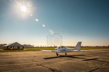 Single-engine small propeller plane on the airfield under sunlight