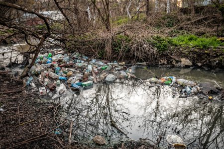 Foto de Diferentes residuos plásticos en el río, contaminación y medio ambiente concepto. - Imagen libre de derechos