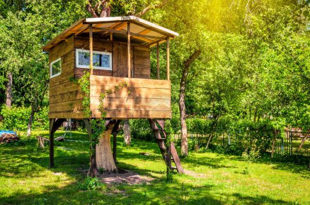 Casa de árbol hecha a mano en jardín verde soleado