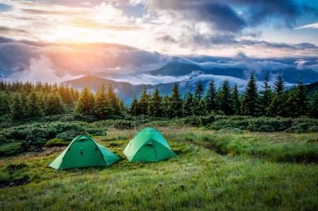 Zwei Touristenzelte in grünen Bergen bei Sonnenuntergang oder Sonnenaufgang