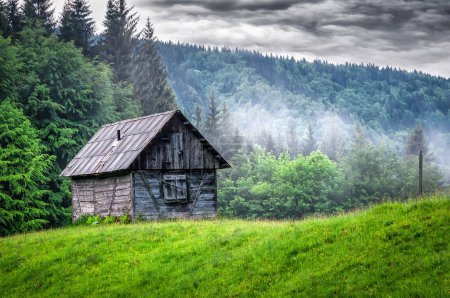 Verlassene Holzhütte in verregneten nebligen Bergen