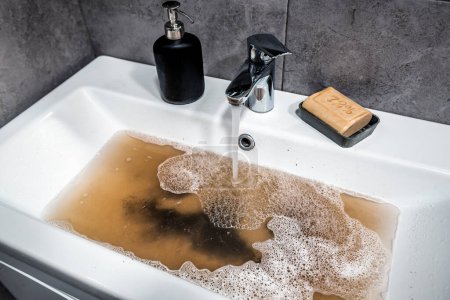 Foto de Fregadero en el baño, fregadero con agua sucia, jabón marrón. Problemas de fontanería. - Imagen libre de derechos