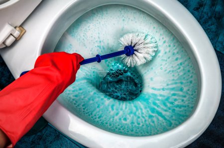 Photo for Hands wearing red gloves using a brush when cleaning the toilet in the bathroom - Royalty Free Image