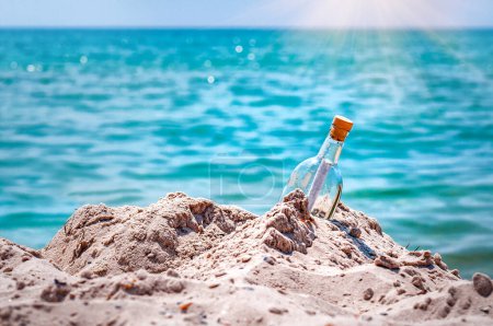 Mensaje en una botella de vidrio en la playa arena bajo la luz del sol