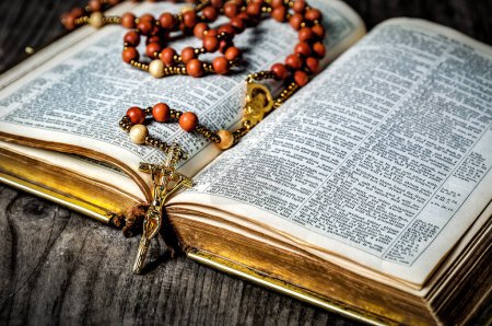 Photo for Old rosary with golden crucifix on old open Bible. Religious theme - Royalty Free Image