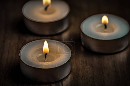 Photo for Three burning round candles on wooden table - Royalty Free Image