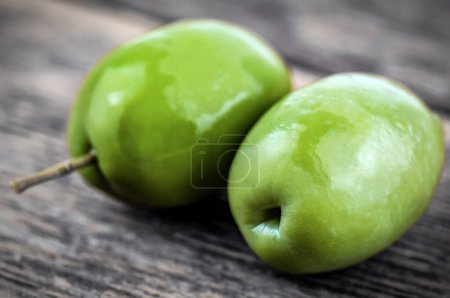 Photo for Two green delicious olives on wooden background - Royalty Free Image