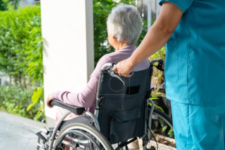 Pflegerin hilft und pflegt asiatische Seniorin oder ältere Patientin im Rollstuhl auf Rampe im Pflegeheim, gesundes starkes medizinisches Konzept
