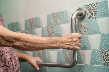 Asiatische Senioren oder ältere Dame Patientin verwenden Toilette Badezimmergriff Sicherheit in Krankenstation, gesunde starke medizinische Konzept.