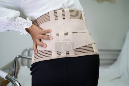 Foto de Asiática señora paciente usando espalda dolor soporte cinturón para ortopédica lumbar con walker. - Imagen libre de derechos