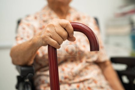 Photo for Asian elderly disability woman holding waling stick, wood cane, round handle, walking aid for help to walk. - Royalty Free Image