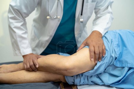 Photo for Asian elderly woman patient show her scars surgical total knee joint replacement Suture wound surgery arthroplasty on bed in nursing hospital ward, healthy strong medical concept. - Royalty Free Image