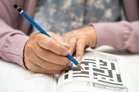 Téléchargez les photos : Alzheimer maladie AD, asiatique femme âgée jouant jeu de puzzle sudoku pour pratiquer la formation du cerveau pour la prévention de la démence. - en image libre de droit