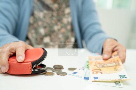 Photo for Asian senior woman holding counting coin money and Euro bnaknotes in purse. Poverty, saving problem in retirement. - Royalty Free Image