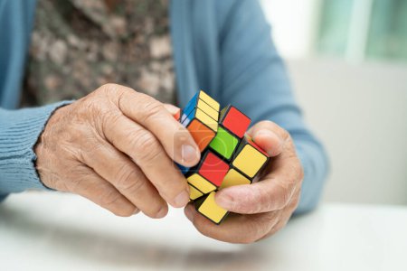 Téléchargez les photos : Bangkok, Thaïlande Août 14, 2023 Alzheimer maladie AD, Asiatique femme âgée jouant Rubik jeu de cube pour pratiquer la formation du cerveau pour la prévention de la démence. - en image libre de droit