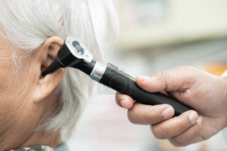 Téléchargez les photos : Audiologiste ou ORL médecin utiliser otoscope vérifier l'oreille de la femme âgée asiatique traitement problème de perte auditive. - en image libre de droit