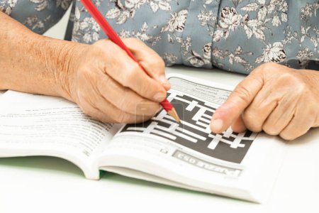 Téléchargez les photos : Alzheimer maladie AD, asiatique femme âgée jouant jeu de puzzle sudoku à pratiquer pour la prévention de la démence. - en image libre de droit
