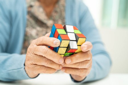 Téléchargez les photos : Bangkok, Thaïlande Août 14, 2023 Alzheimer maladie AD, Asiatique femme âgée jouant Rubik jeu de cube pour pratiquer la formation du cerveau pour la prévention de la démence. - en image libre de droit