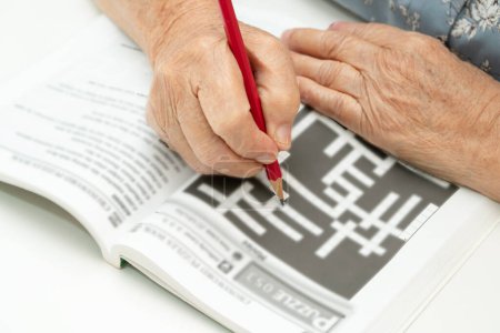 Téléchargez les photos : Alzheimer maladie AD, asiatique femme âgée jouant jeu de puzzle sudoku à pratiquer pour la prévention de la démence. - en image libre de droit