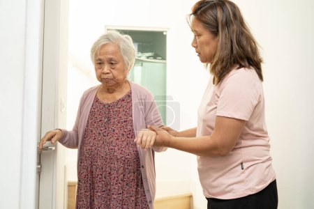 Caregiver help asian or elderly old woman support up the stairs in home.