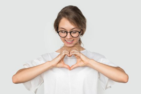 Photo for Pretty woman confessingg in love, making heart gesture, happy expression, posing over white background. Relationship concept - Royalty Free Image