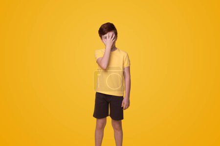 Téléchargez les photos : Young caucasian boy put hand on face, facepalm epic fail isolated on yellow background studio portrait. People lifestyle concept - en image libre de droit