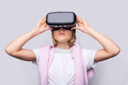 Portrait of young woman playing VR game wearing VR headset, half body shot. Young generation choose virtual reality relaxation concept.