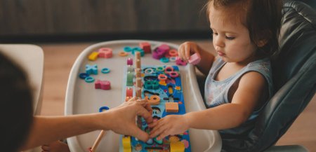 Foto de Mujer y niña jugando con juguetes educativos juntos en la guardería. Juego de madera con diferentes colores y números. Juego intecactivo para smart - Imagen libre de derechos