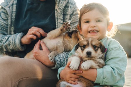 Foto de Hermosa mujer con una niña pequeña abrazando a un cachorro pequeño. Concepto de familia, mascotas, animales domésticos y personas. Madre joven con niña y perro. El concepto de - Imagen libre de derechos