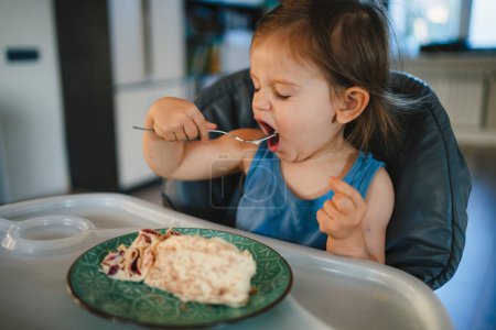 Téléchargez les photos : Adorable caucasienne tout-petit fille manger le repas sur son propre. Le concept de l'auto-alimentation. BLW. - en image libre de droit