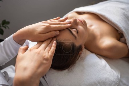 Photo for Beautiful caucasian woman enjoying facial massage with closed eyes at spa salon. Relaxing treatment in medicine. Skin and body care. - Royalty Free Image