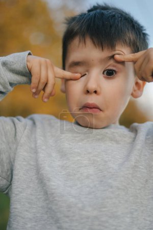 Photo for Caucasian boy making funny gestures and faces looking at camera posing outdoors. - Royalty Free Image
