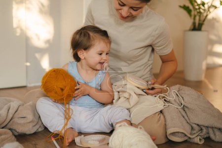 Madre e hija sentadas en el suelo en casa tejiendo. Proyecto artesanal Concepto de bordado DIY Punch needle.