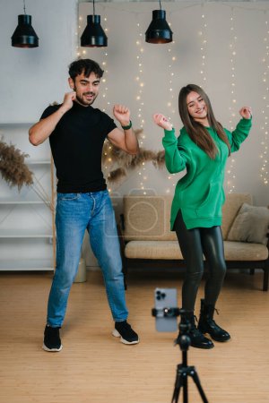 Man and woman recording video dances using smartphone at home. Gen Z talent people play video selfie shoot app for show share viral story.