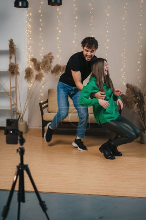Young man and woman recording video challenge on mobile phone. Female content creator having fun filming dance tutorial.