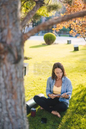 Foto de Mujer bastante adulta leyendo una novela de literatura de libros en el parque de jardín de verano al aire libre, soñando con imaginar. Educación o lectura de deberes - Imagen libre de derechos