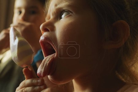 Ein junges Mädchen streckt freudig ihre Zunge heraus, während sie ihr Eis genießt, und zeigt eine spielerische Geste, während sie die süße Leckerei genießt