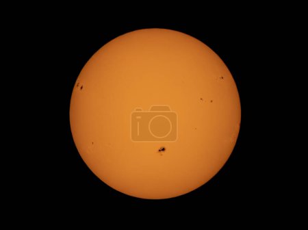 Photo for The orange coloured afternoon sun glowing with many sunspots using a homemade solar filter. - Royalty Free Image