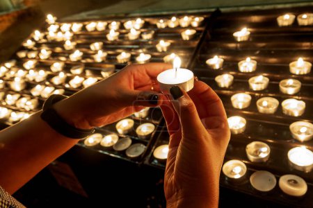 Foto de Mujer encendiendo candeles en el Santuario de San Miguel Arcángel, Monte Sant 'Angelo, Italia - Imagen libre de derechos
