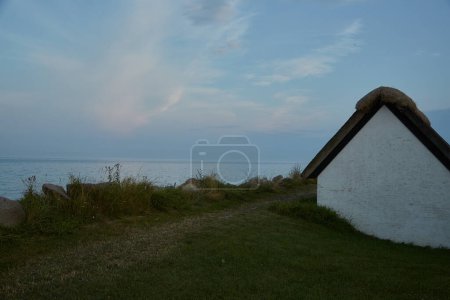 Photo for Smal cabin with thatched roof by the sea at dusk. - Royalty Free Image