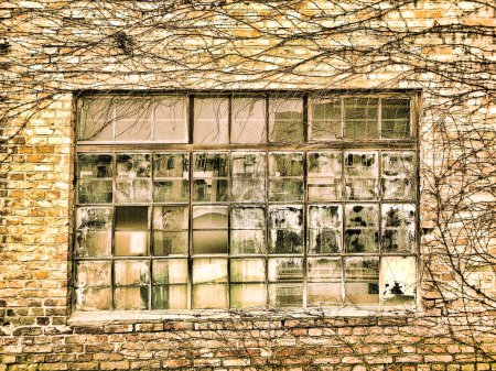 Una vieja ventana con un marco de metal en una fachada de ladrillo clinker