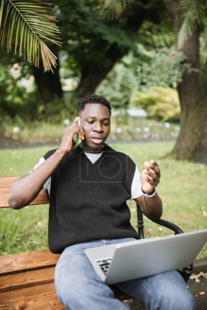 Young African man talking on phone disputing over computer, stressed, unsatisfied. Disappointed, confused, angry male arguing with technical online support or customer service. Bad connection concept