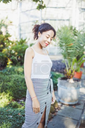Photo for Young African American multiracial woman in midi pencil skirt with front button slit in park or street outdoor. White t shirt mock up. Fall season - Royalty Free Image