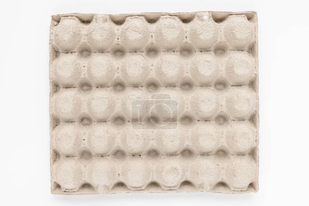 A top view of a beige egg carton displaying symmetrical circular indentations